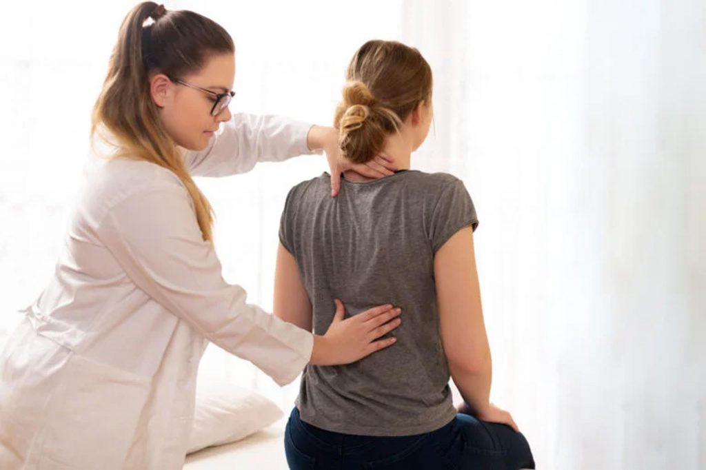 A pregnant woman receives back pain alleviation from her therapist in SportsMed center