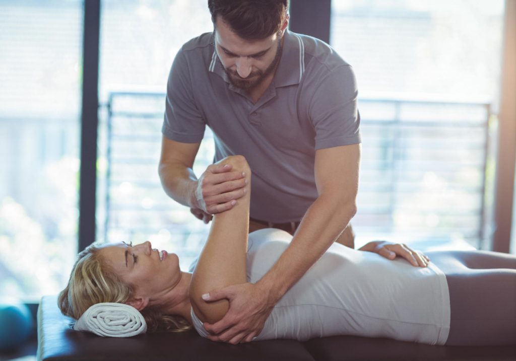 At SportsMed clinic, a therapist offers versatile exercises to assist a woman's progress