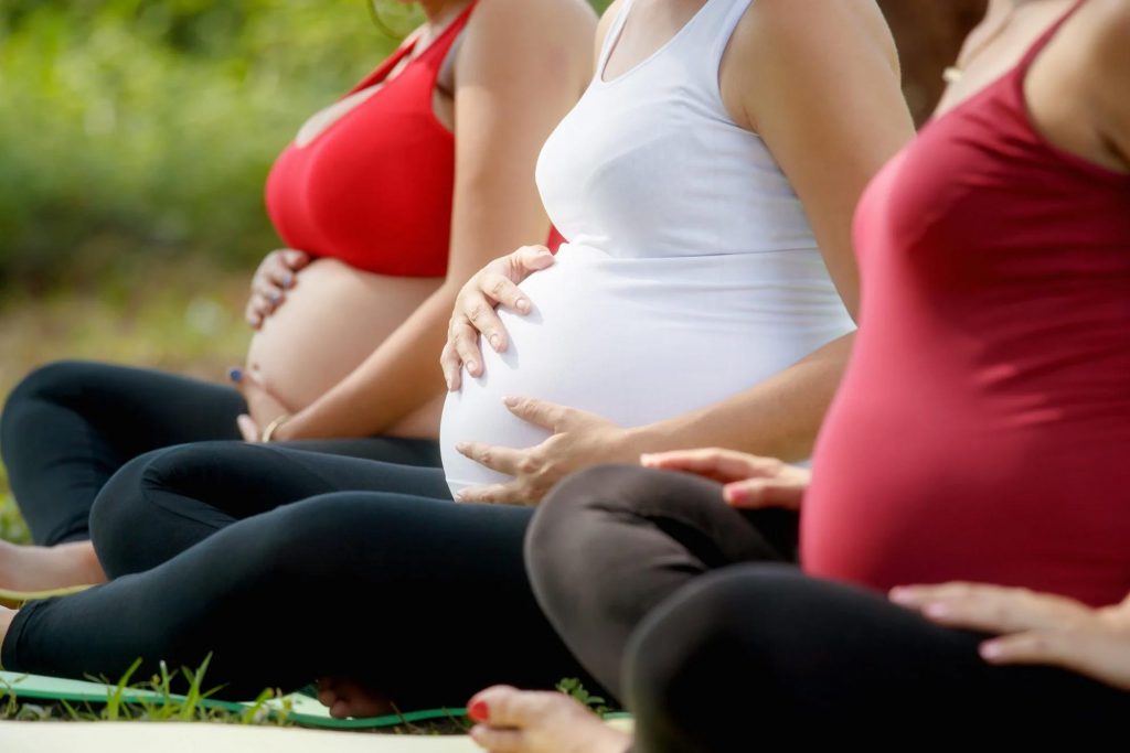 Pregnant women are gently caressing their pregnant bellies during a prenatal session