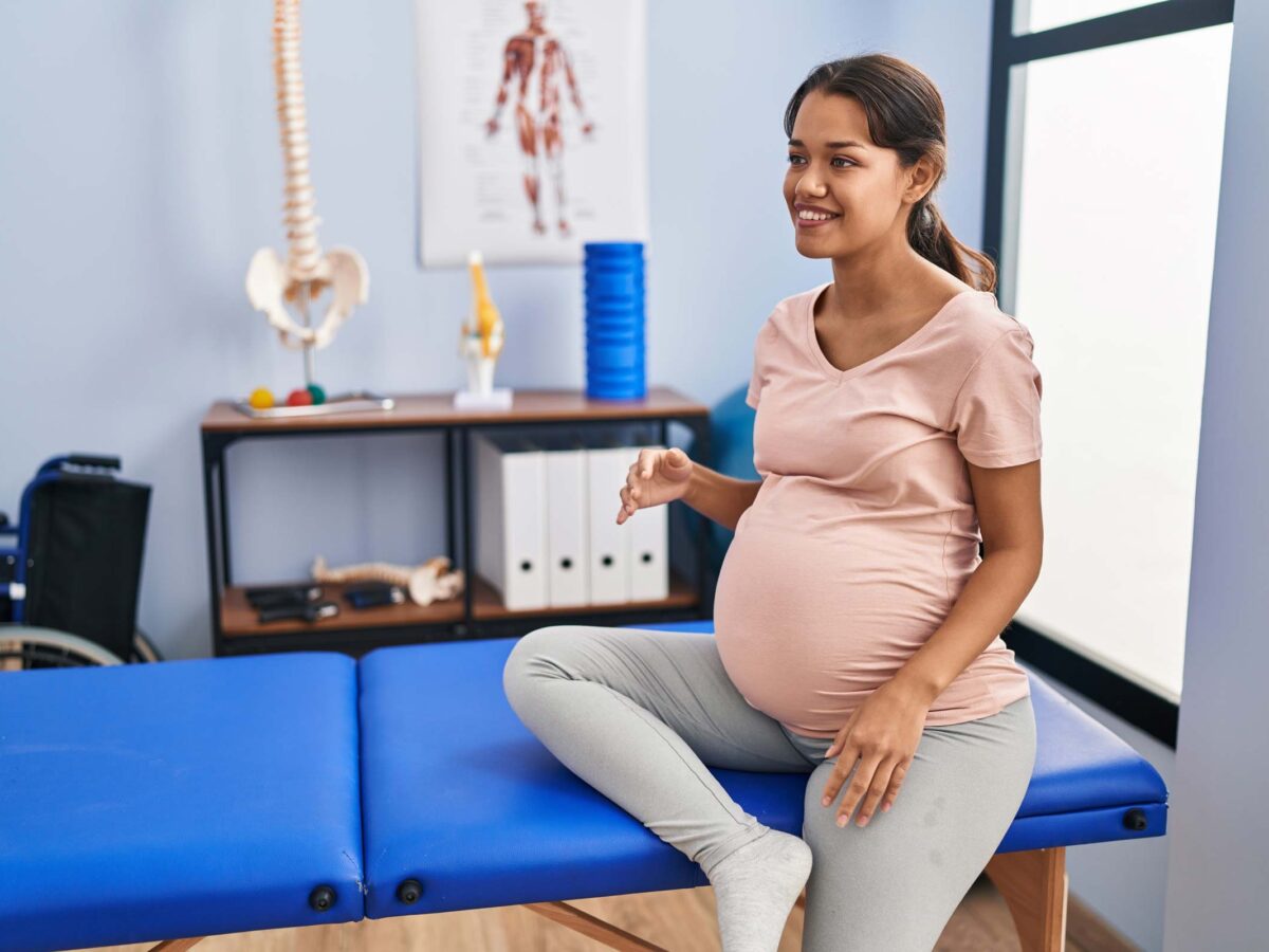 Pregnant woman sitting on an examination table in a doctor's office