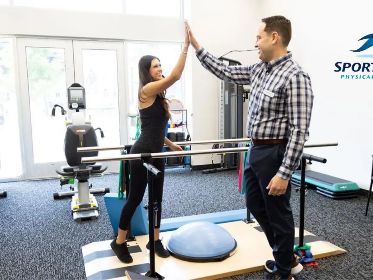 Sportsmed therapists and patient give a high five doing exercises.