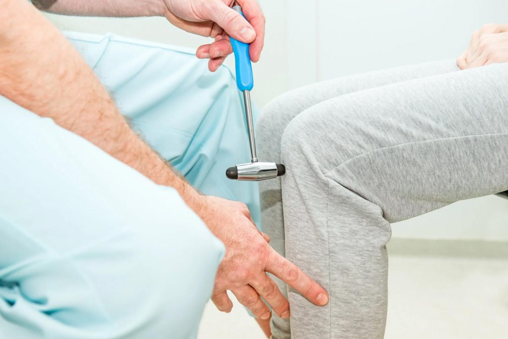 A female patient underwent a neurological physical examination at the SportsMed clinic, where a neurologist used a hammer to test her knee reflex.