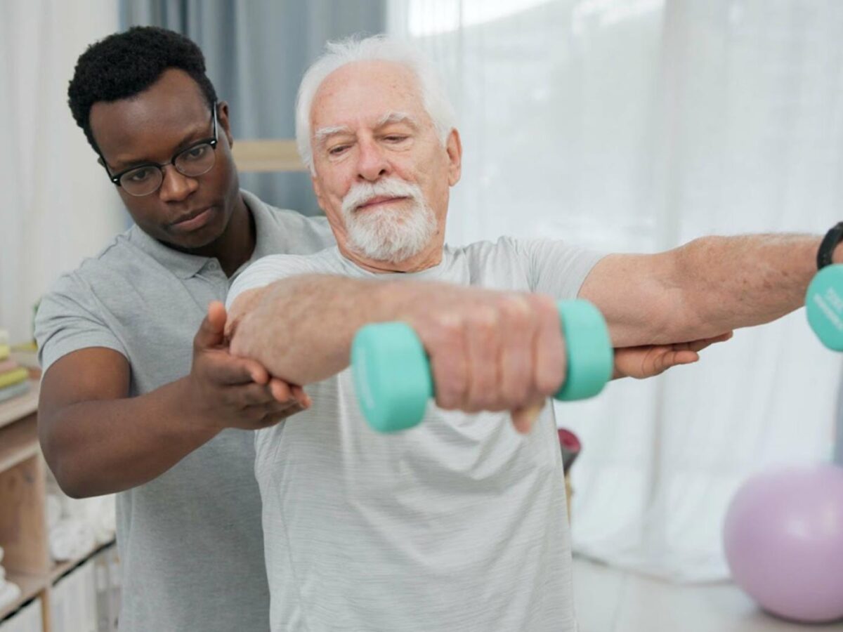A therapist instructing an elderly man on exercise techniques.
