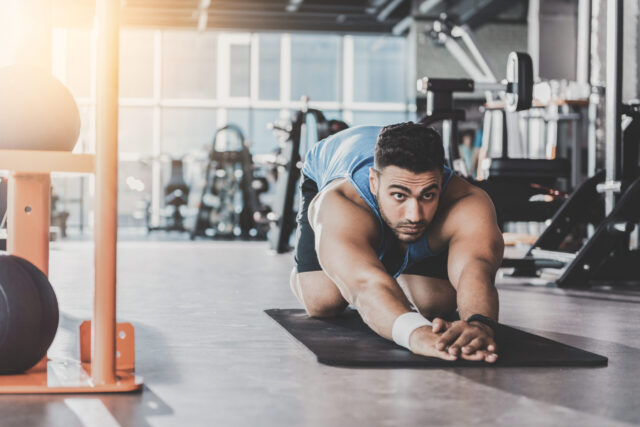 unshaven man exercising on mat in a gym