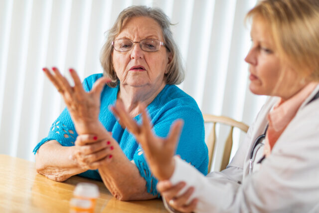 Female hand therapist talking with senior adult woman