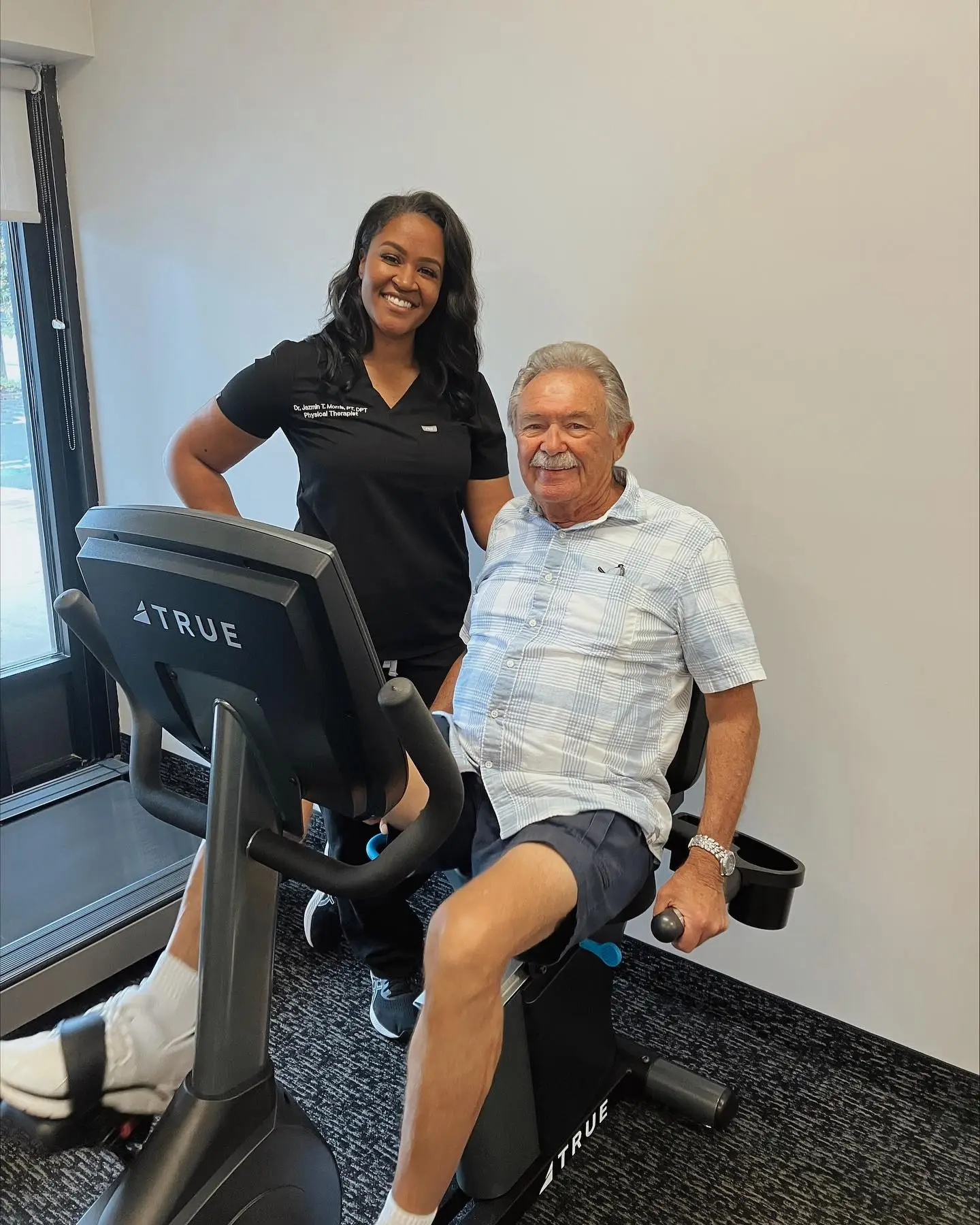 Smiling SportsMed Staff with patient on exercise bike