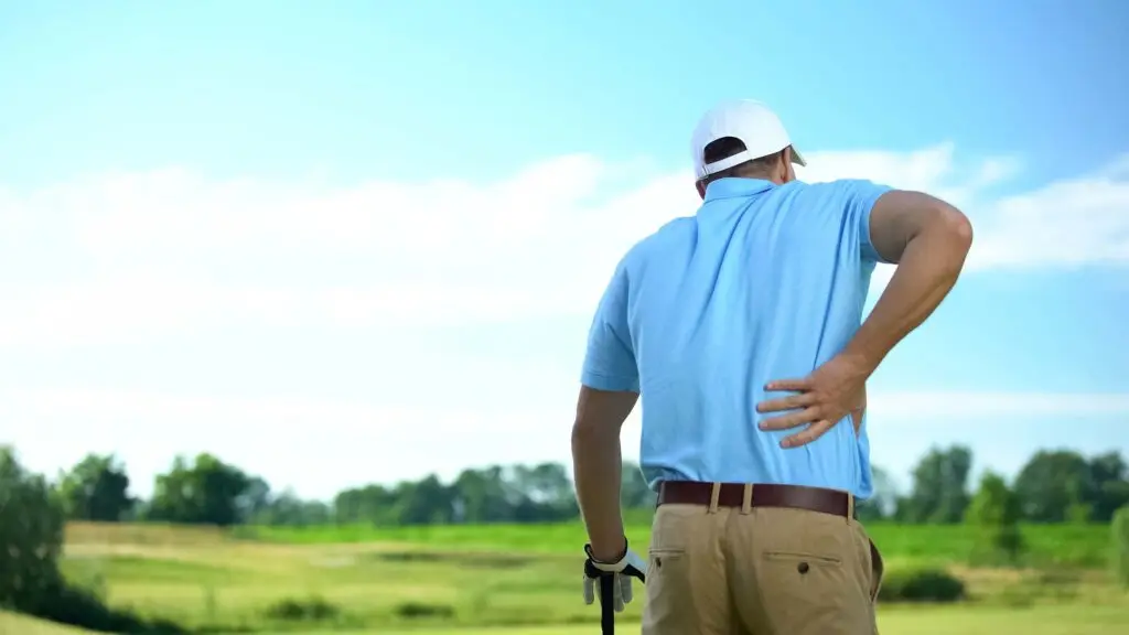 Golfer reaching to his back in pain.