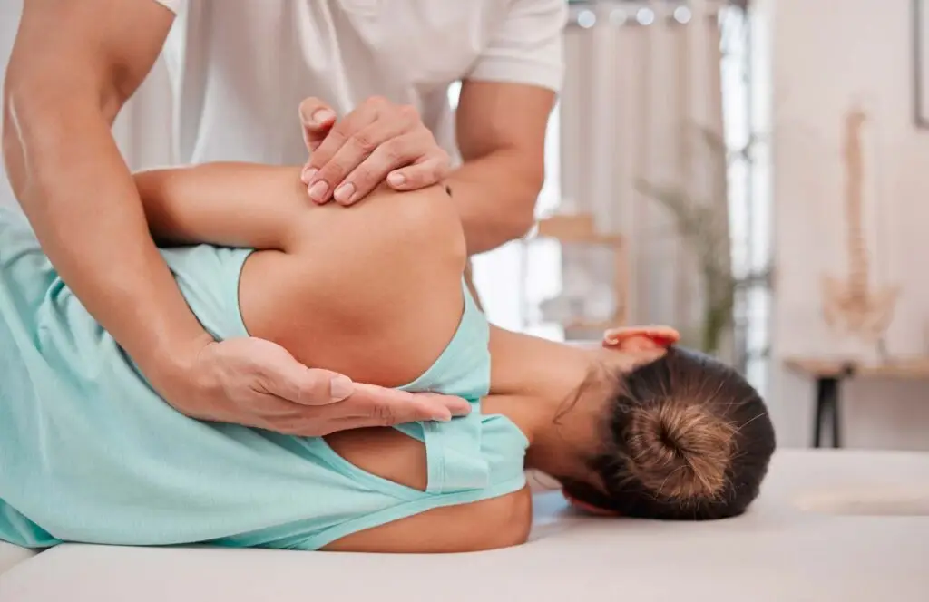Physical Therapist examining patient's back on table.