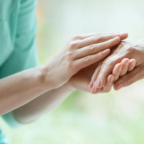 Care Taker gently soothing elderly person's hand